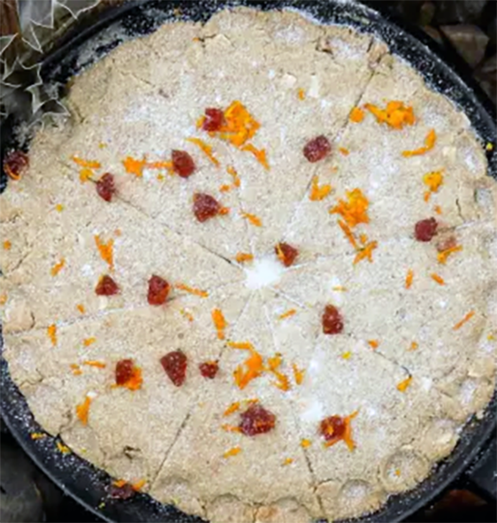 Scottish yule bannon viewed from above showing its fluted edges and garnish of orange zest and plumped raisins
