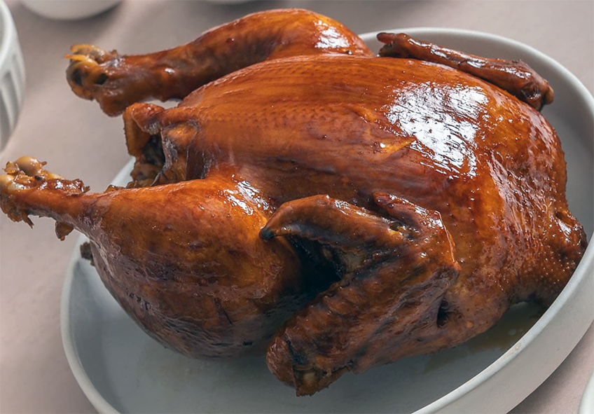 a whole soy sauce chicken resting in a high-sided dish