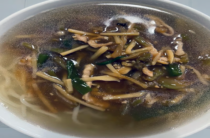 shredded pork and noodle soup served in a white bowl