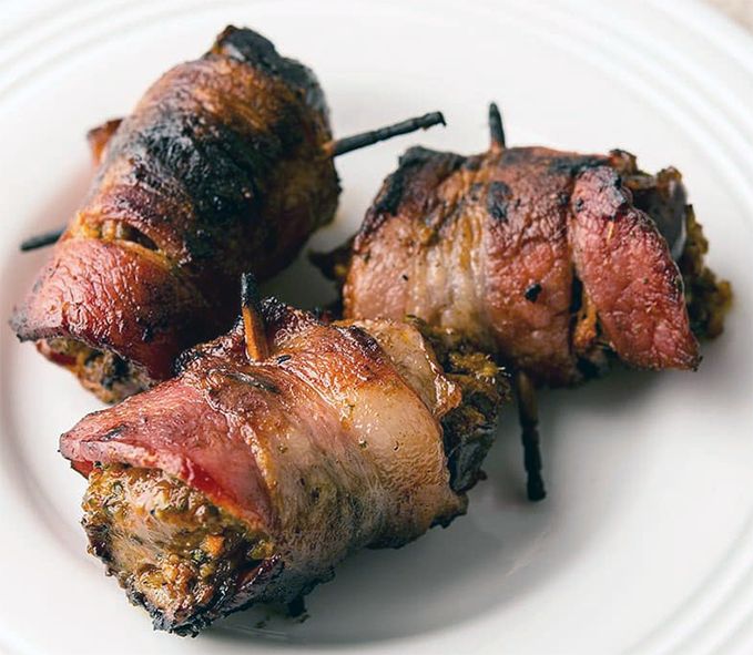 three barbecued bacon-covered pigeon breasts on a plate