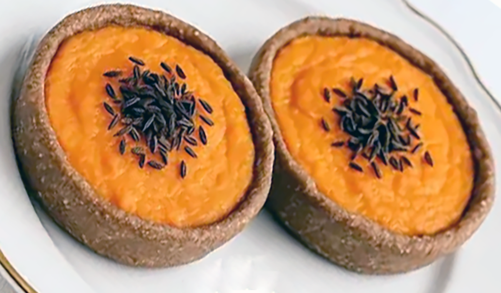 two Sklandrausis on a plate, garnished with caraway seeds