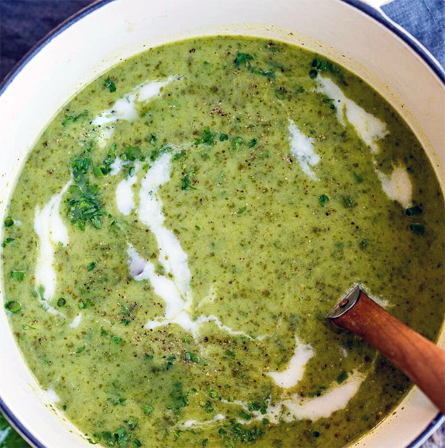 sorrel soup in a soup pan with a garnish of sour cream