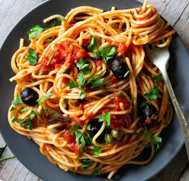 spaghetti with puttanesca sauce piled on a plate