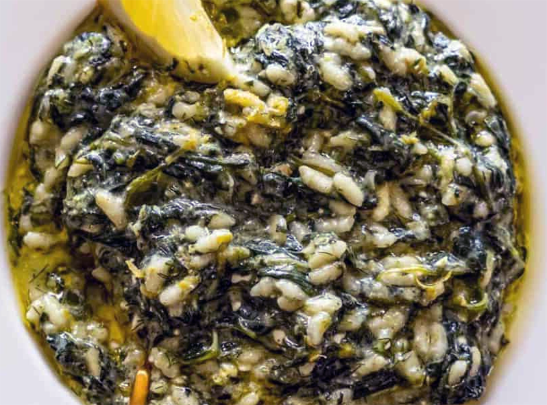 Spanachorizo, rice pilaff with spinach served in a bowl with a wedge of lemon
