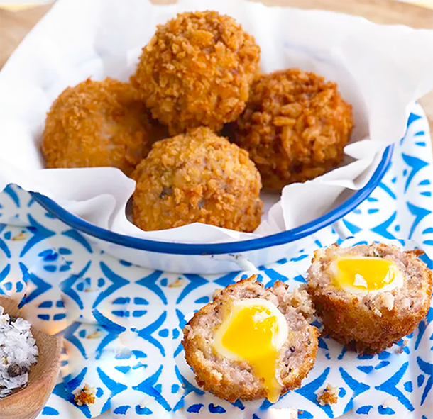 spicy mini scotch eggs in a bowl, with one split in half in front
