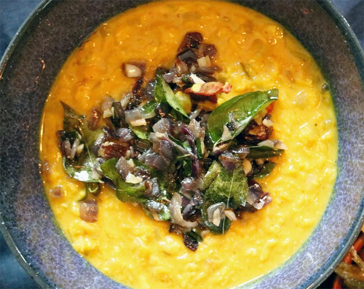 yellow dal curry served in a bowl with a topping of curry leaf tempering fried in coconut oil