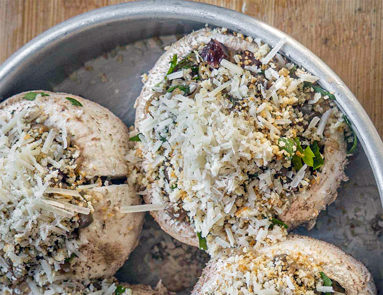 stuffed shaggy parasol mushroom caps in a round metal roasting tin