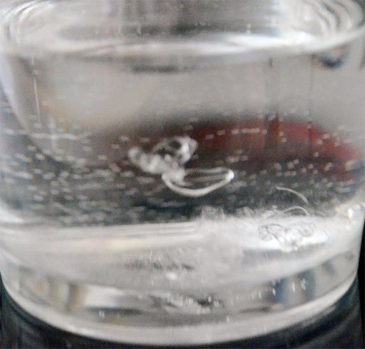 Sugar syrup forming threads in a glass of water