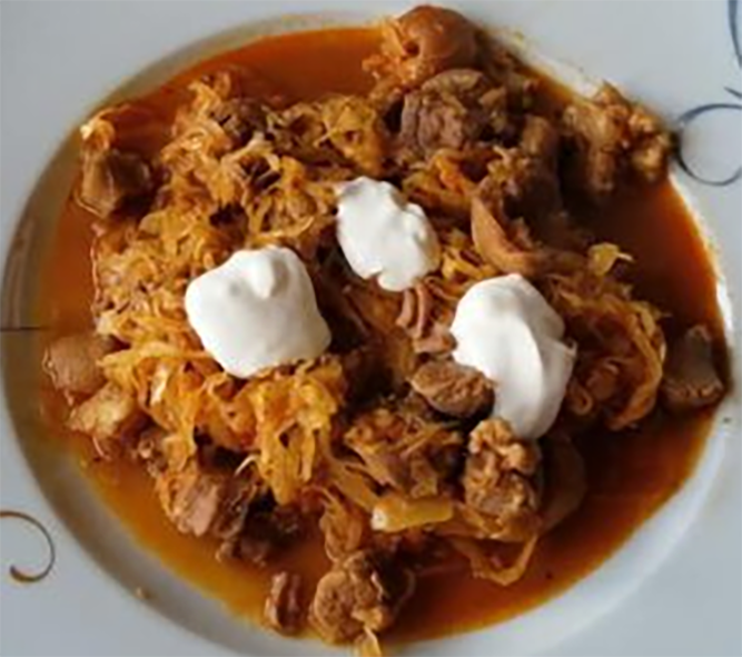 pork goulash topped with sour cream served on a bed of pasta