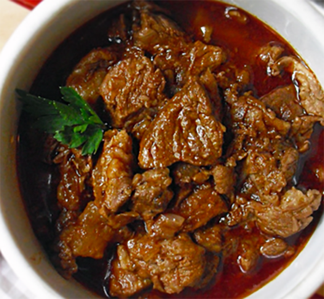 mutton stew in a pan garnished with a sprig of mint
