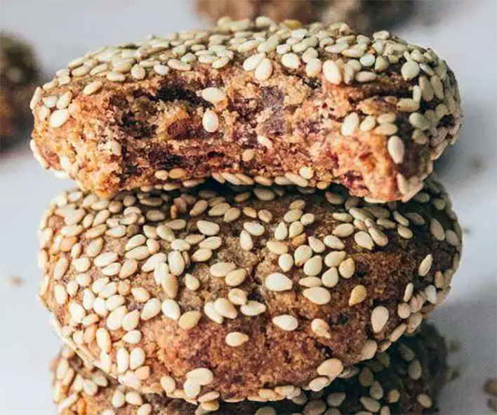 stack of tahini biscuits with date syrup one with a bite taken out of it