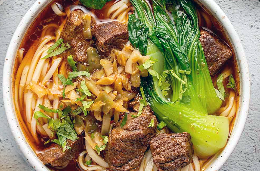 taiwanese beef noodle soup with beef layered on noodles served in a bowl