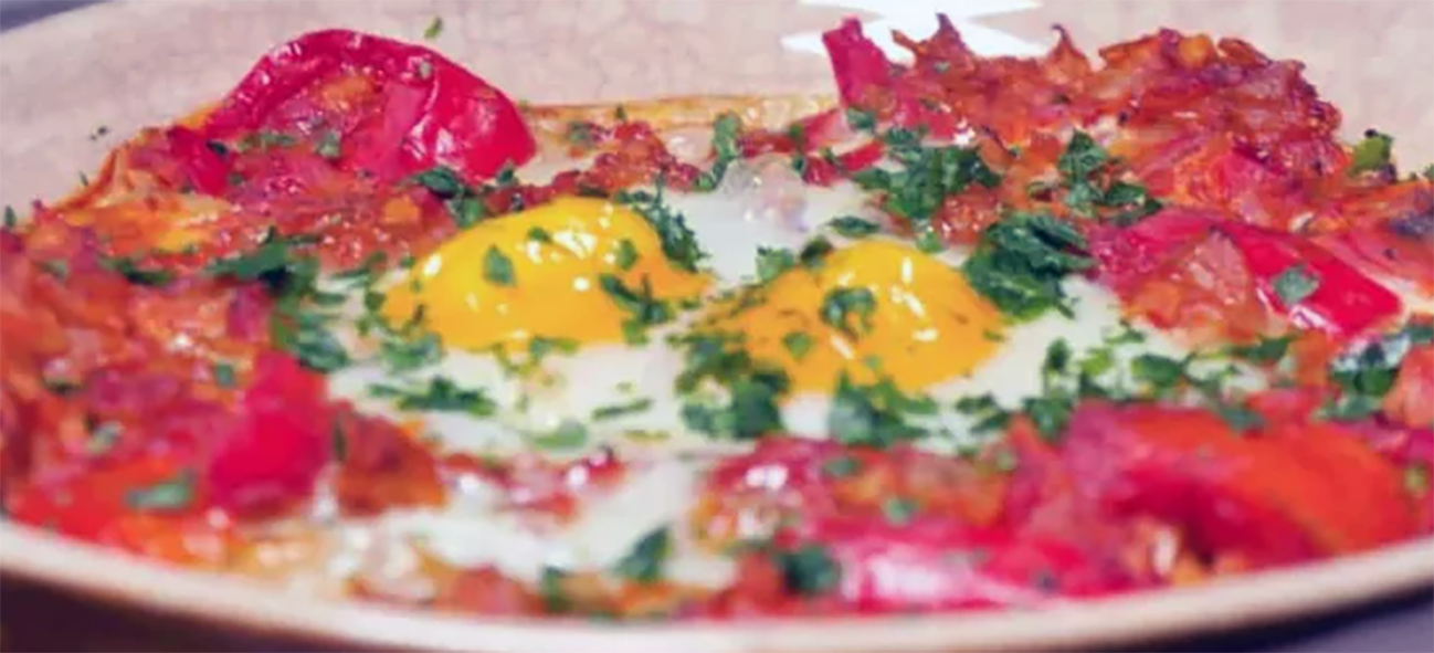Algerian tchektchouka topped with eggs and served on a plate