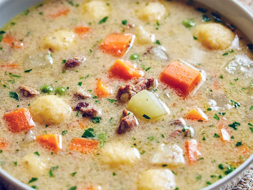 wild boar soup with vegetables and sour cream served in a soup bowl</a>