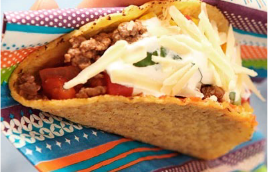 Tex-Mex beef taco topped with cheese in a coloured paper towel</a>