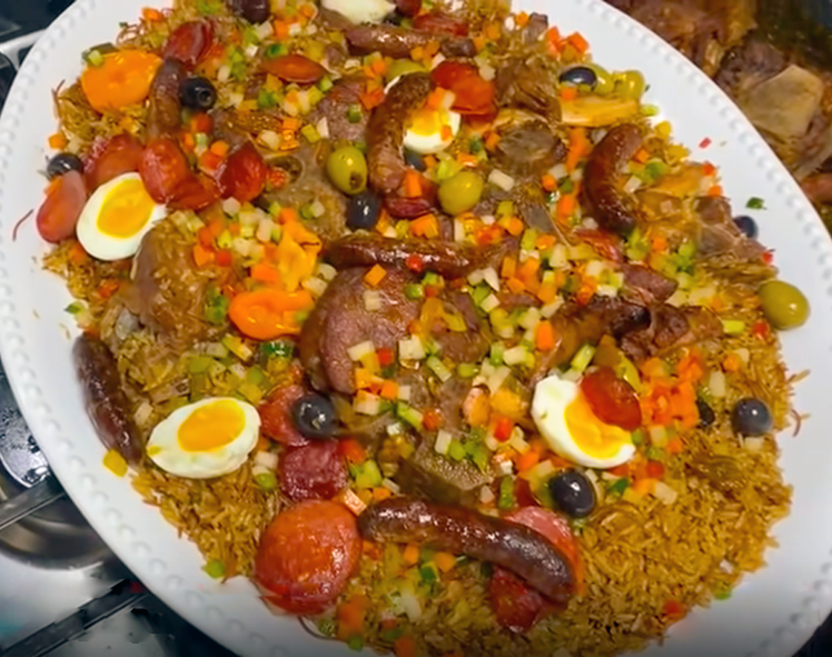 mixed meat and rice served on a large dish with diced vegetables, whole habanero chillies, halved hard-boiled eggs and sliced tomatoes