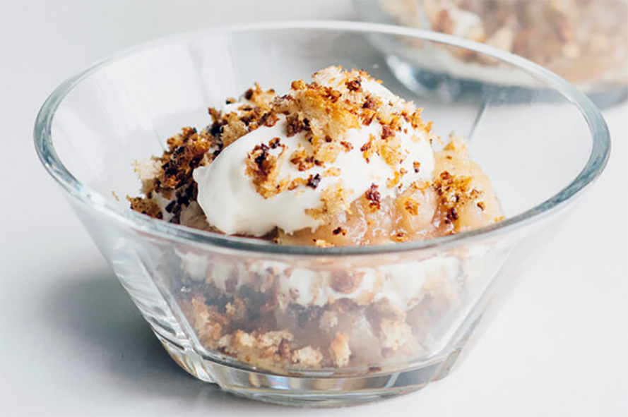 layered dessert of rumbled oatcakes, mashed cloudberries and whipped cream in a conical glass