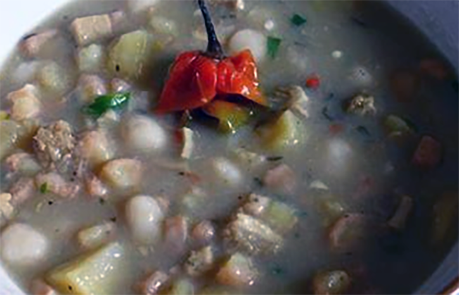 breadfruit and pork stew served in a bowl garnished with a habanero chilli
