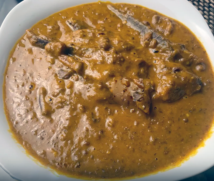 beans and meat in a red oil base with onion and spices served in a bowl
