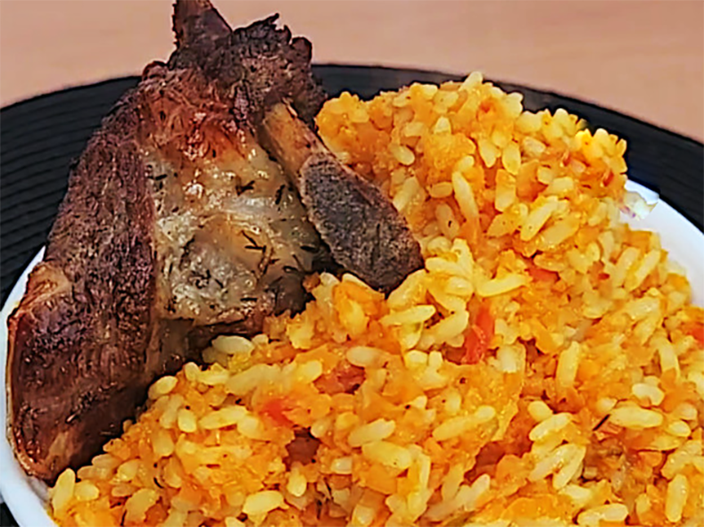 tomato-less jollof rice in a bowl topped with pieces of fried meat