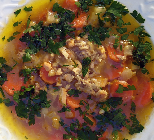 Hungarian chicken soup garnished with flat-leaf parsley in a soup bowl