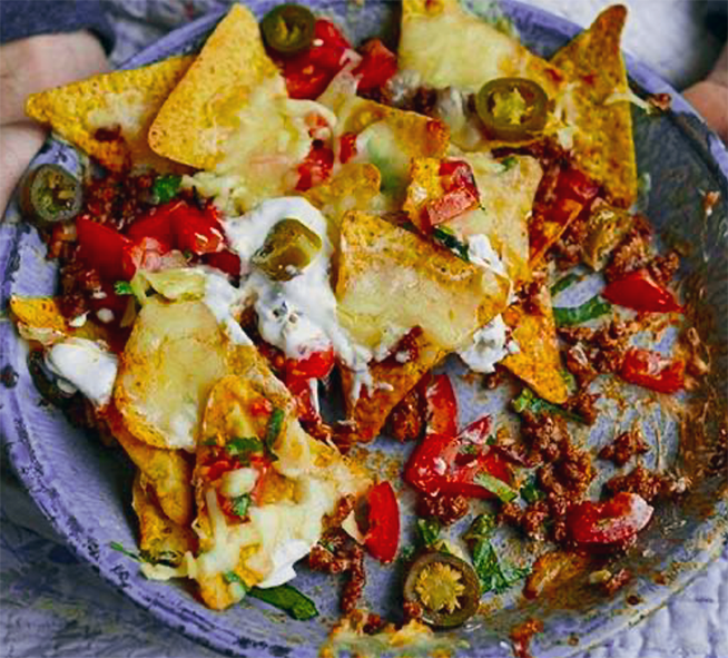 nachos topped with minced beef, jalapeños and sour cream on a plate