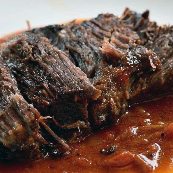 beef pot roasted with a tomato sauce served sliced on a plate with the sauce