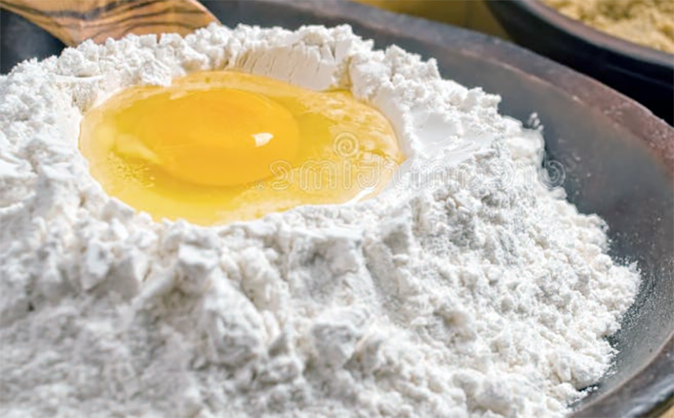 Flour in a bowl with well in the flour and eggs in the well