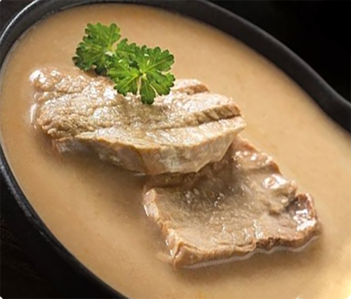 pork chops in a sour cream sauce garnished with a sprig of parsley