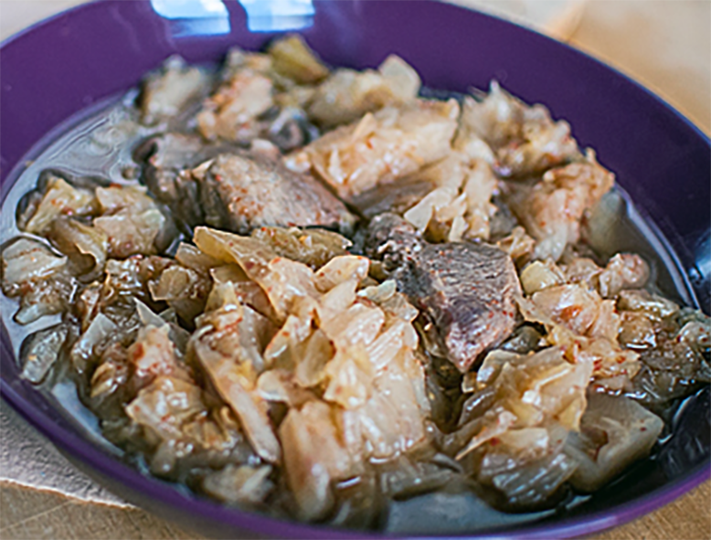 stew of brined cabbage and pork in a purple dish